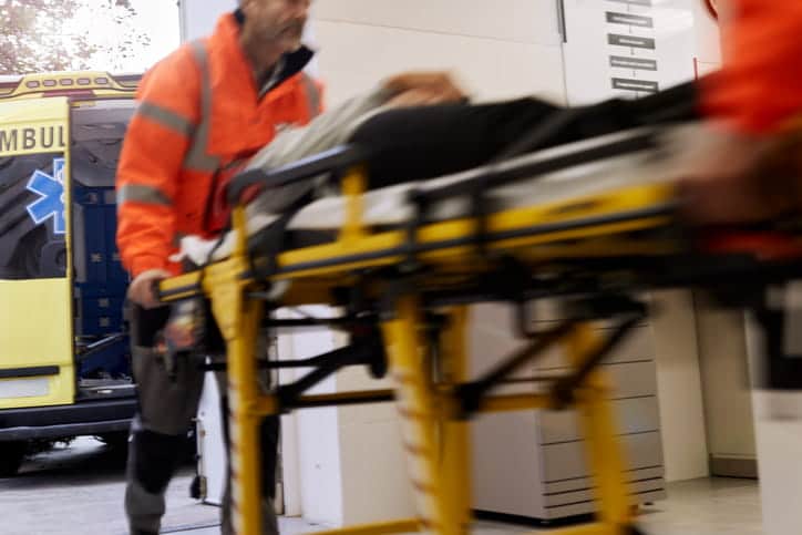 EMTs rushing a stretcher into a hospital. Everything but the ambulance is out of focus.