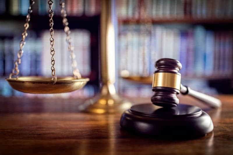 A closeup of a gavel with the scales of justice in the background.