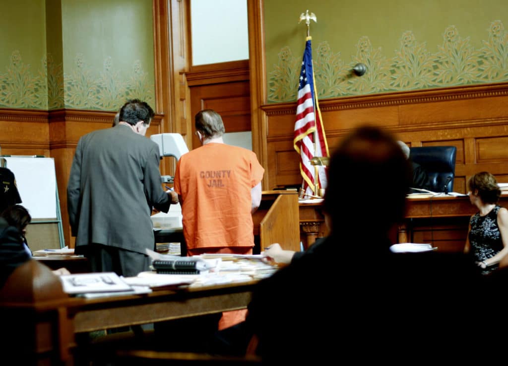 A lawyer standing with his client before the judge in a criminal trial.