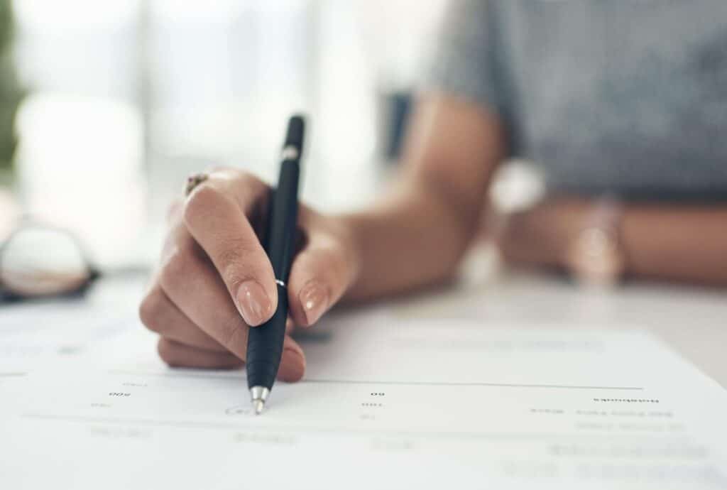person filling out paperwork with a pen