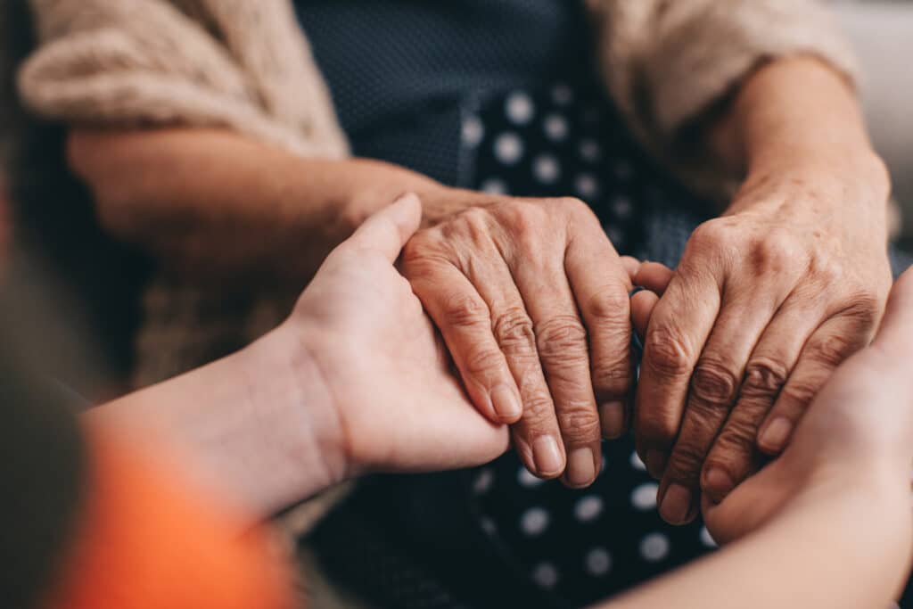 hands of 2 people held together while grieving