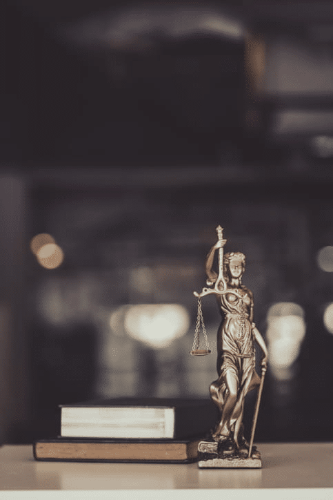 A stack of books and a Lady Justice statue on the desk of a wrongful death lawyer.