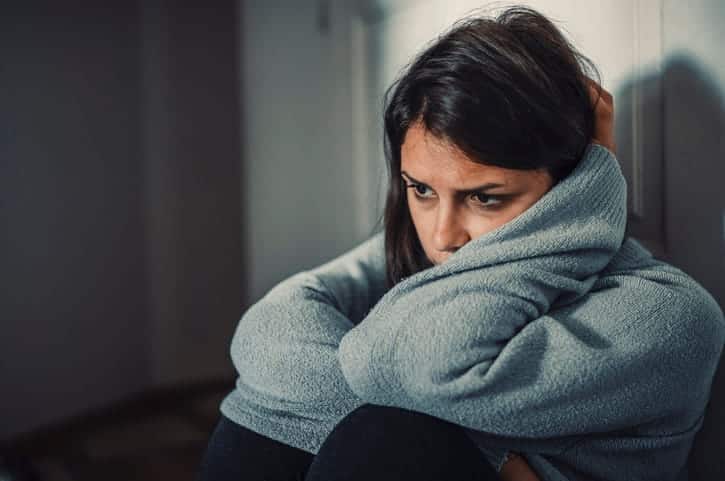 A woman holding her head in distress after experiencing loss of enjoyment of life from an accident.