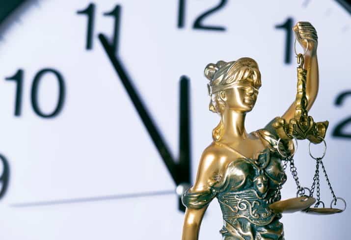 A Lady Justice statue in front of a clock.