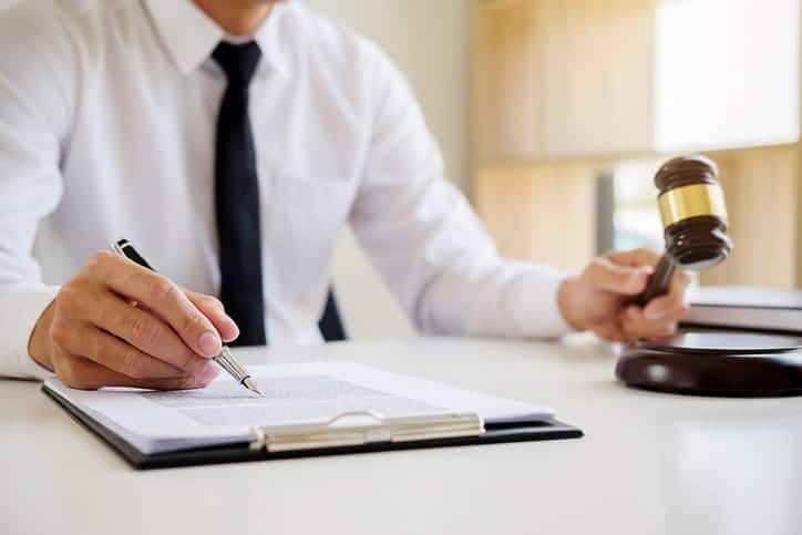 A wrongful death attorney uses a gavel at his desk while working on paperwork for a client. 