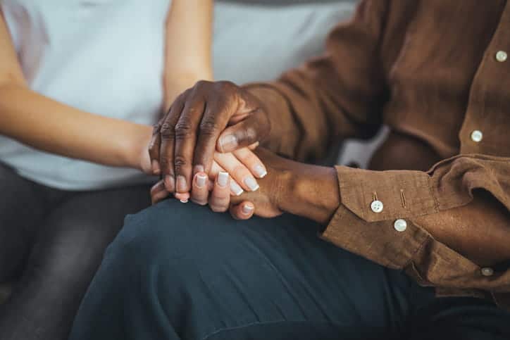 Two people clasping hands and grieving together after losing a loved one to a wrongful death. 