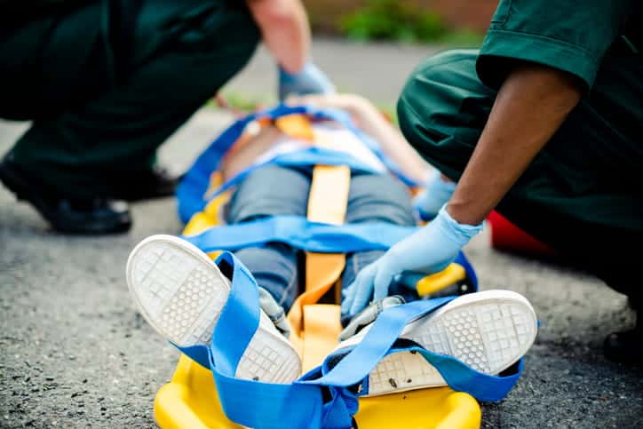 Medical professionals are strapping a person onto a stretcher after a catastrophic injury.