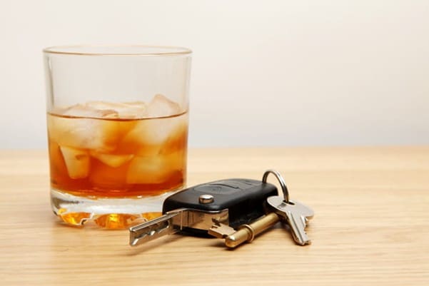 An alcoholic drink next to a set of car keys.